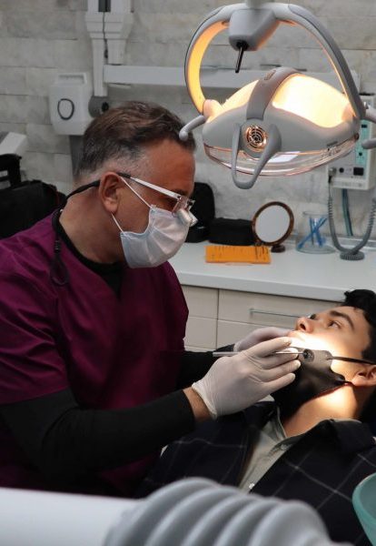 Dr.Enrique Franco Hombre en un consultorio dental, vestido con un uniforme médico, sentado en una silla.